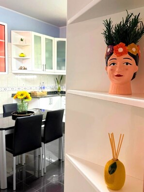 A modern kitchen with white cabinets, a dining table with chairs, and a decorative vase with a floral arrangement. - Refúgio do Atalho by Stayguest (Santana)