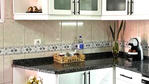 A kitchen with white cabinets, a granite countertop, and a tiled backsplash. - Refúgio do Atalho by Stayguest (Santana)