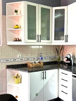 A kitchen with white cabinets, a granite countertop, and a tiled backsplash. - Refúgio do Atalho by Stayguest (Santana)