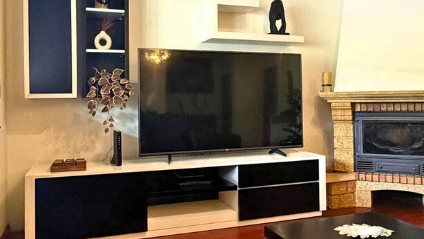 A living room with a flat-screen TV on a white stand, a fireplace, and a modern entertainment unit with shelves. - Refúgio do Atalho by Stayguest (Santana)