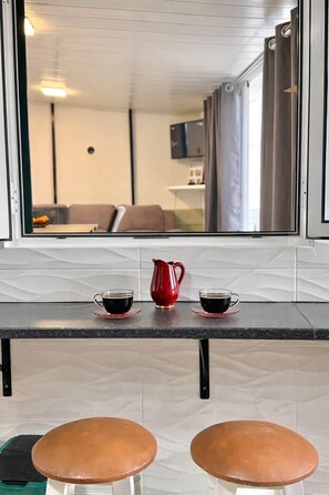 A kitchen counter with a coffee setup and two stools. - Yara House by Stayguest (Câmara De Lobos)