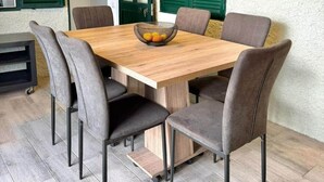 A dining area with a wooden table, six chairs, and a fruit bowl. - Yara House by Stayguest (Câmara De Lobos)
