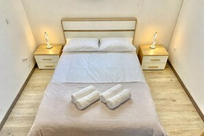 A neatly made bed with white linens, two bedside tables with lamps, and a wooden floor. - Yara House by Stayguest (Câmara De Lobos)