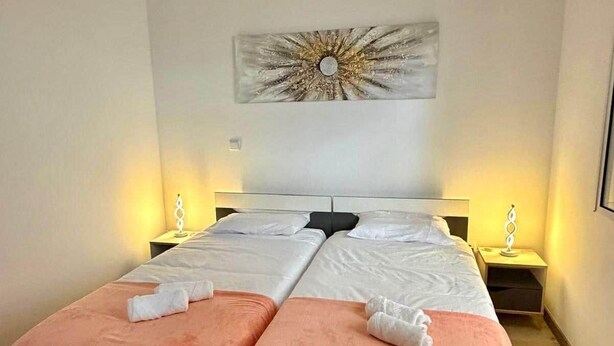 A double bed with matching pillows, two bedside tables with lamps, and a wall-mounted artwork. - Yara House by Stayguest (Câmara De Lobos)