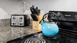 Eine Küche mit einem schwarzen Frigidaire-Herd, einem blauen Wasserkocher und einem Toaster auf einer Arbeitsplatte aus Granit.