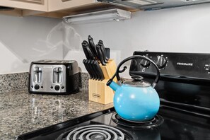 Eine Küche mit einem schwarzen Frigidaire-Herd, einem blauen Wasserkocher und einem Toaster auf einer Arbeitsplatte aus Granit.