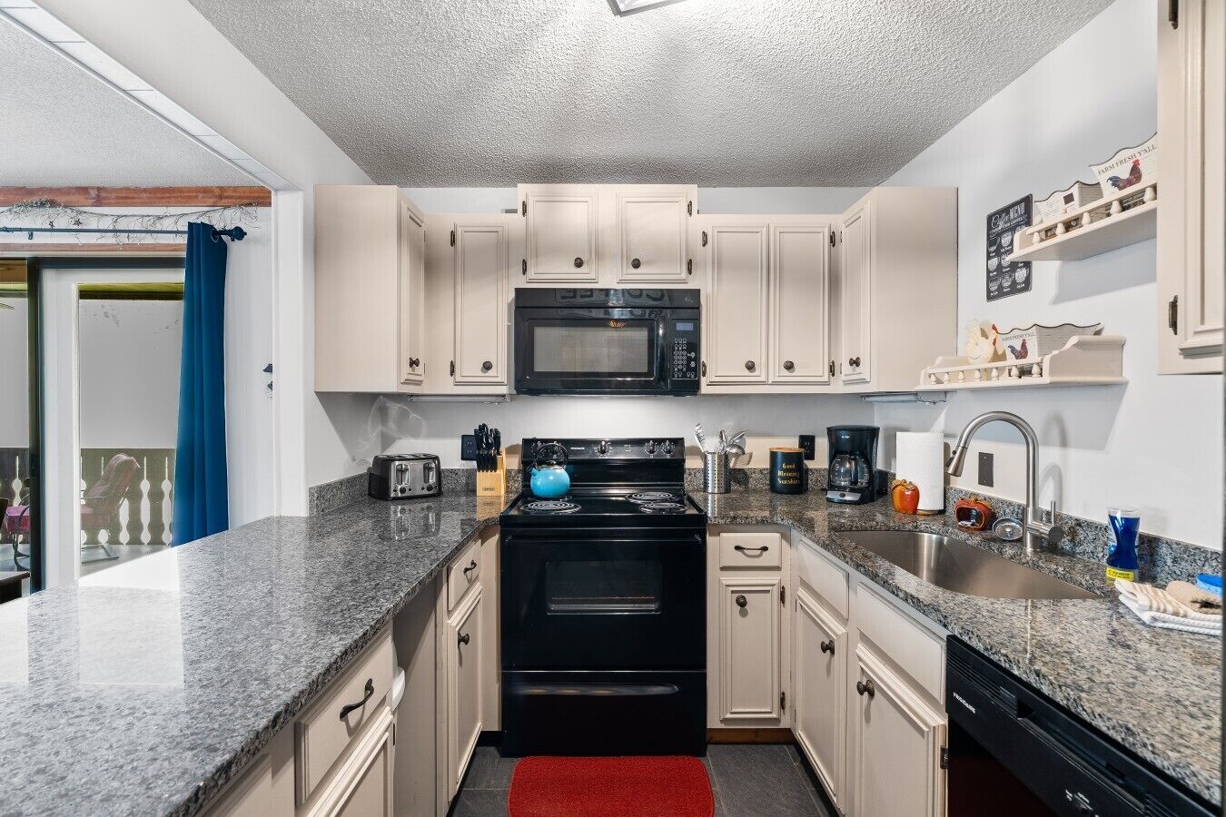 A compact kitchen with a microwave, stove, and sink.