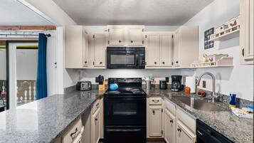 A compact kitchen with a microwave, stove, and sink.