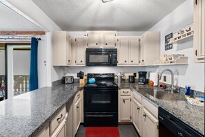 A compact kitchen with a microwave, stove, and sink.