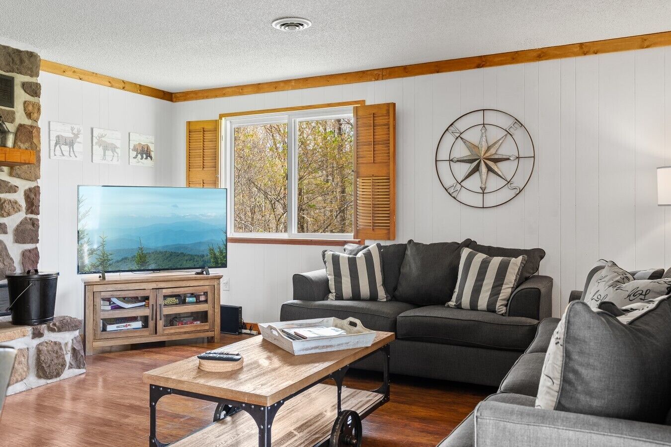 A living room with a television, a sofa, a coffee table, and a wall-mounted compass decoration.