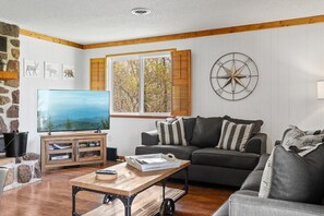 A living room with a television, a sofa, a coffee table, and a wall-mounted compass decoration. - Mountain View Loft | Cozy Single-Level Retreat (Gatlinburg)
