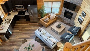 A cabin interior with a kitchen, dining area, and seating with a fireplace. - Serene MTN Cabin: Indoor Pool, Hot Tub, & Game Room! (Pigeon Forge)