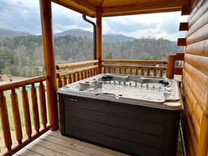 A hot tub on a wooden deck with a view of a forested landscape. - Serene MTN Cabin: Indoor Pool, Hot Tub, & Game Room! (Pigeon Forge)