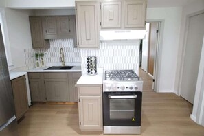 A kitchen with a gas stove, oven, and white cabinets. - Modern apt in E Boston/Walk to Airport (Boston)