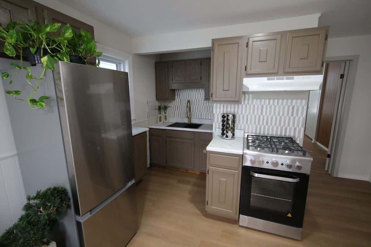 A modern kitchen with a stainless steel refrigerator, a gas stove, and wooden cabinets.