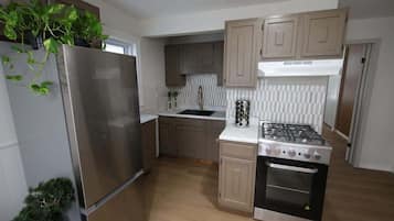 A modern kitchen with a stainless steel refrigerator, a gas stove, and wooden cabinets.