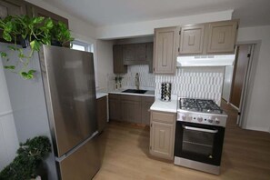 A modern kitchen with a stainless steel refrigerator, a gas stove, and wooden cabinets.