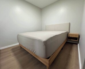 A bedroom with a bed, wooden headboard, and a nightstand.