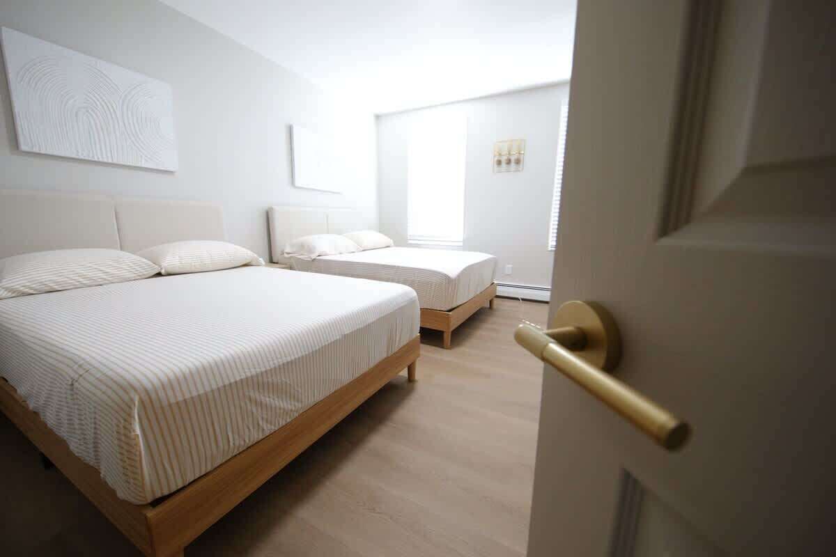 A hotel room with a large bed, a smaller bed, and a door with a golden handle.