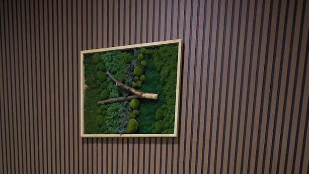 Un lit bien fait, avec une couvre-lit à rayures, une tête de lit en bois et une table de chevet dotée d’un tiroir.
