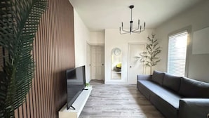 Un salon moderne avec un téléviseur à écran plat, un canapé gris et un mur d’accent en bois.