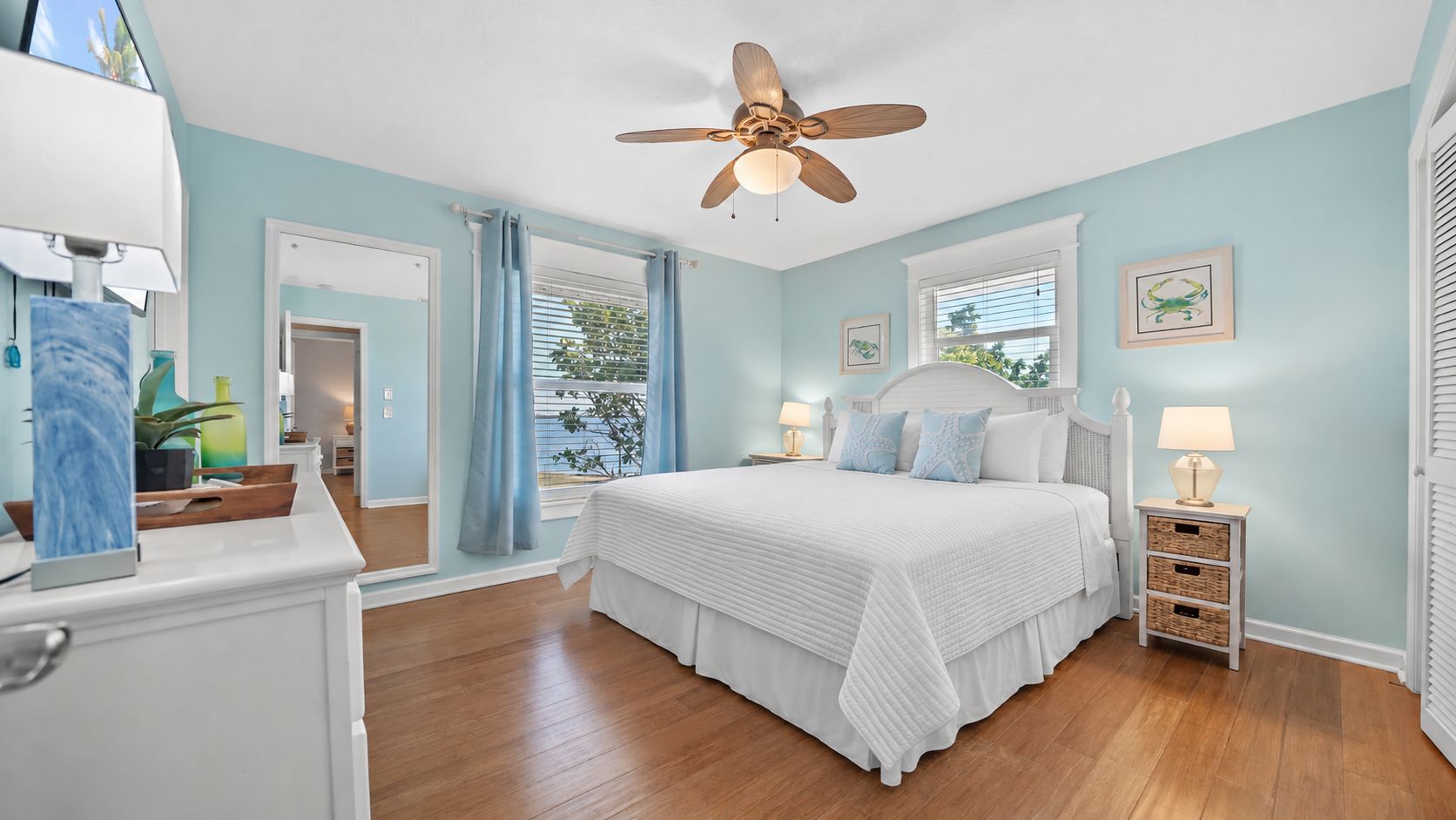 A bedroom with a bed, bedside tables, a ceiling fan, and a window with curtains.