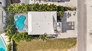 Vista aérea de una propiedad con piscina, un patio cubierto y abundante vegetación.