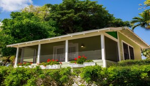 Ein eingeschossiges Gebäude mit überdachter Veranda, umgeben von üppiger Vegetation und Bäumen.
