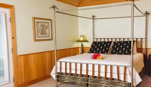 Ein Himmelbett mit einem gemusterten Bettbezug, ein gerahmtes Bild an der Wand und eine Lampe.