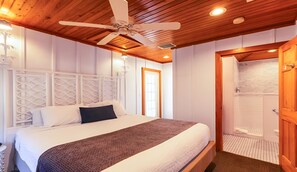 Ein Schlafzimmer mit einem Bett, Holzboden und einer Tür zu einem Badezimmer.