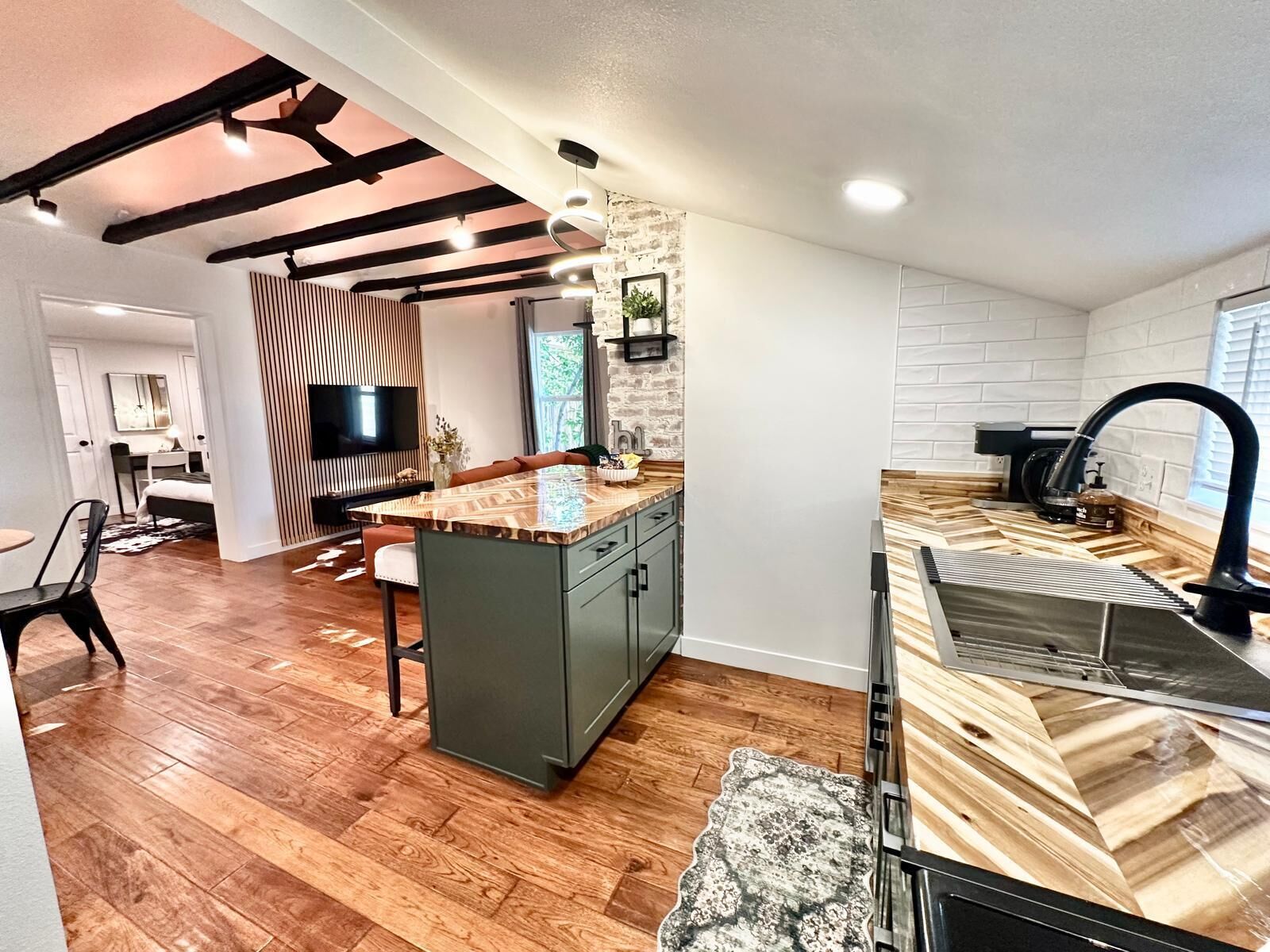 A modern kitchen with a central island, built-in appliances, and a stone accent wall.