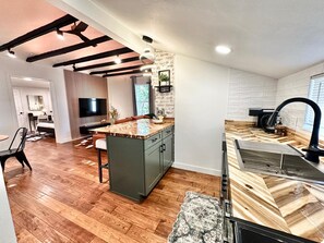 A modern kitchen with a central island, built-in appliances, and a stone accent wall. - The Bison Cottage bungalow, a private boutique retreat in Cheyenne. (Cheyenne)