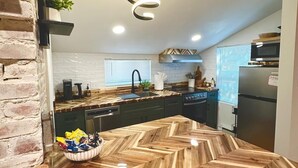 A modern kitchen with a herringbone wood countertop, built-in appliances, and a unique ceiling light fixture. - The Bison Cottage bungalow, a private boutique retreat in Cheyenne. (Cheyenne)
