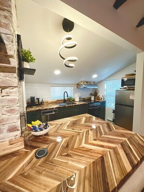 Eine moderne Küche mit Zinkeneinleger-Holzausziehtisch, integrierten Geräten und einer außergewöhnlichen Deckenleuchte.