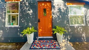 A house with a dark gray exterior, a brown front door, and two potted plants on either side. - The Bison Cottage bungalow, a private boutique retreat in Cheyenne. (Cheyenne)