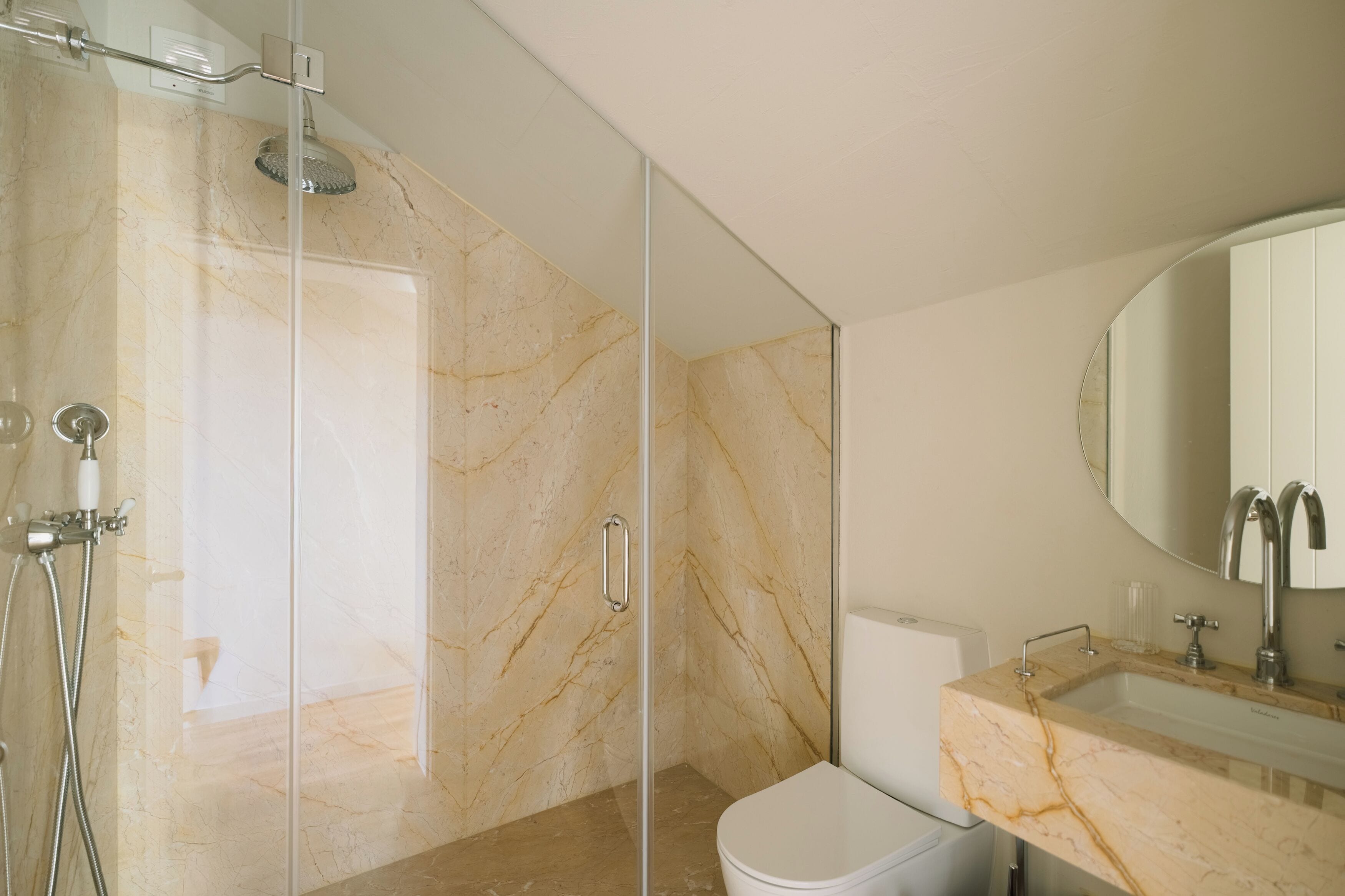 A modern bathroom with a glass-enclosed shower, a marble vanity, and a toilet.