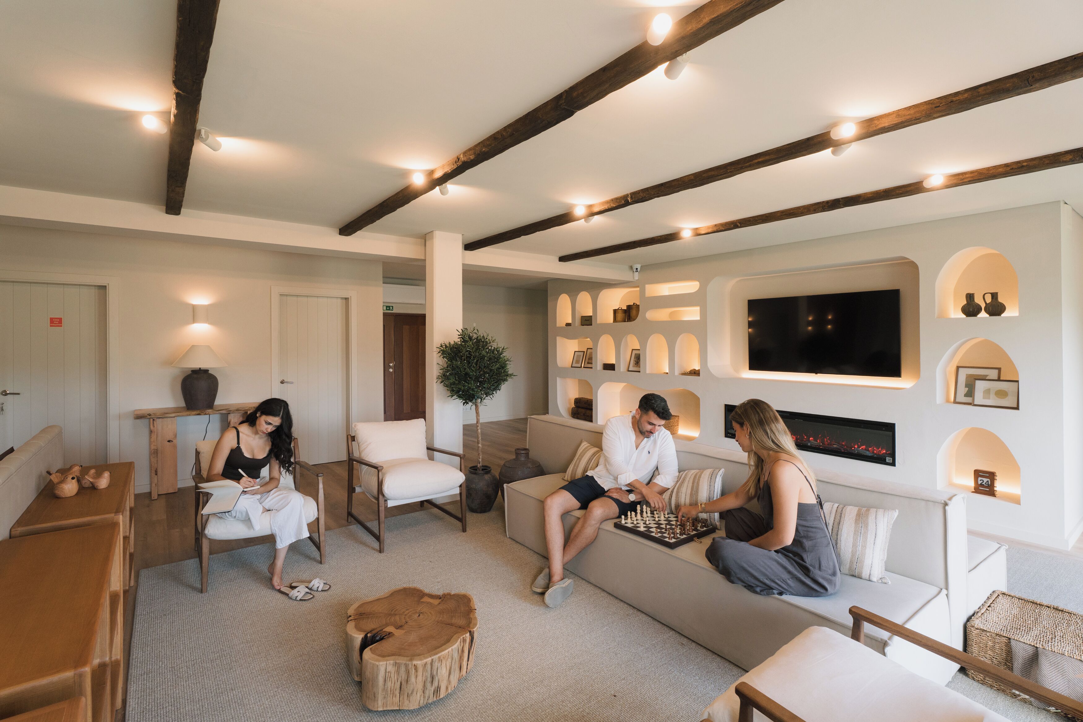 Una sala de estar moderna con chimenea, vigas de madera y un televisor grande.