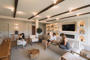 Una sala de estar moderna con chimenea, vigas de madera y un televisor grande.