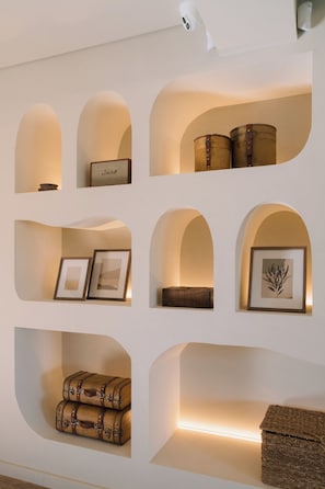 Una pared con múltiples hornacinas de arco, cada una con objetos diversos como cuadros enmarcados, un altavoz pequeño y elementos decorativos.