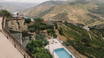 A pool with a view of terraced vineyards and a distant body of water.