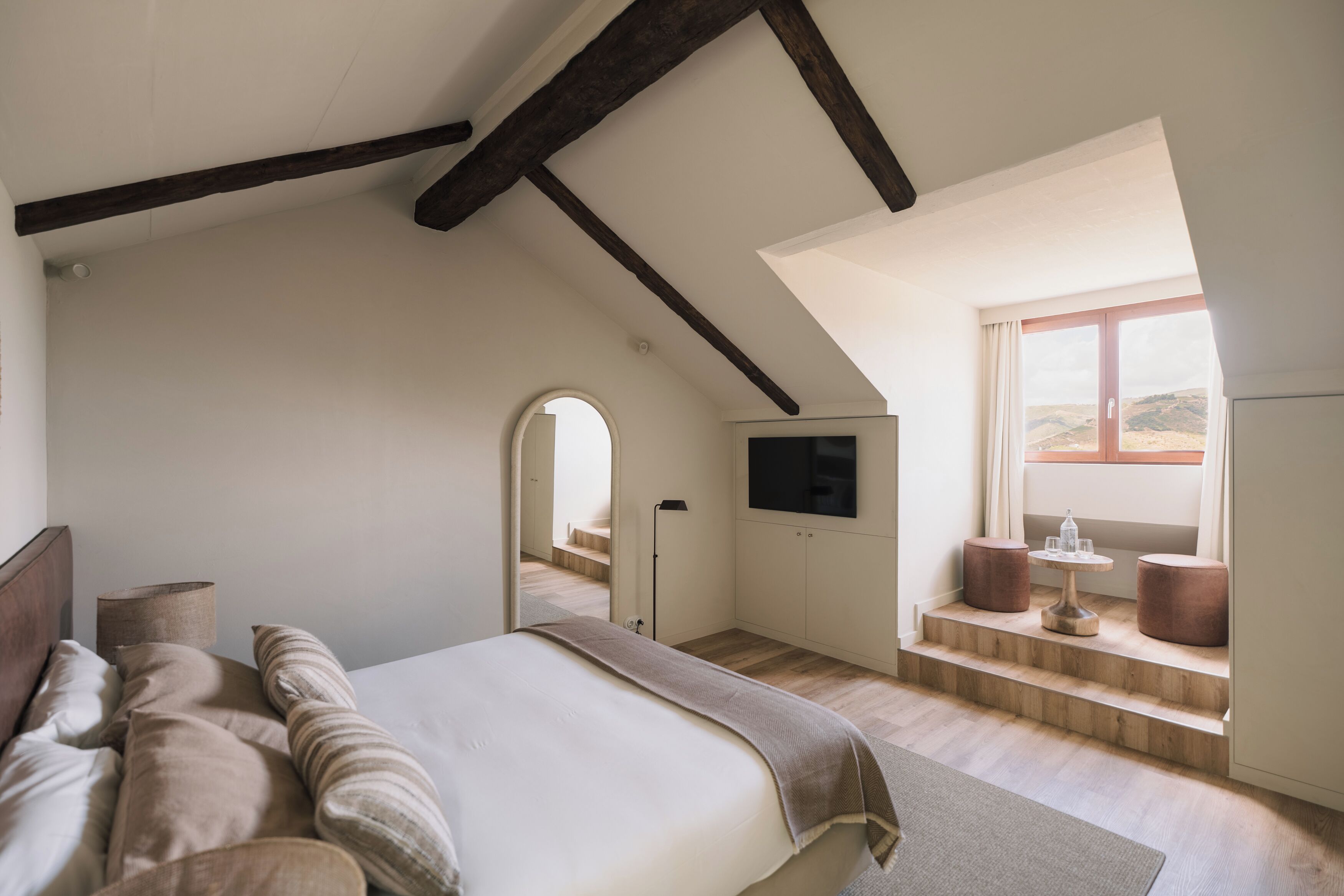 Quarto com cama, televisão, janela com vista e escada.
