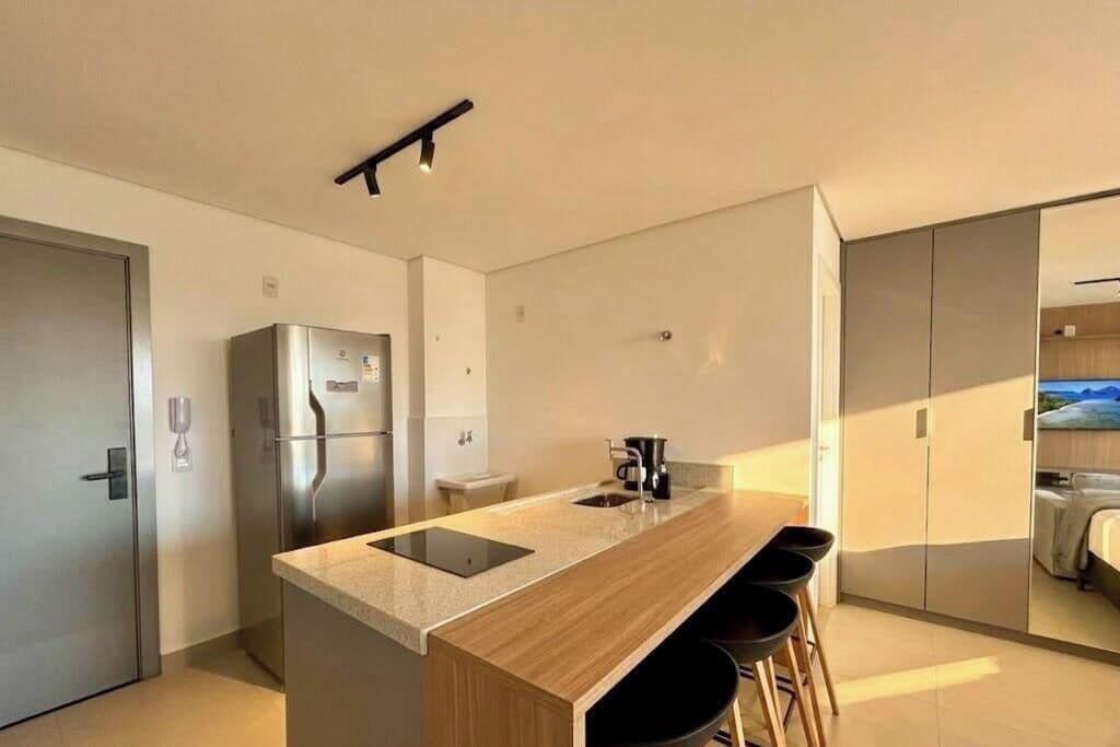 A modern kitchen with a central island, stainless steel appliances, and a view into a bedroom.