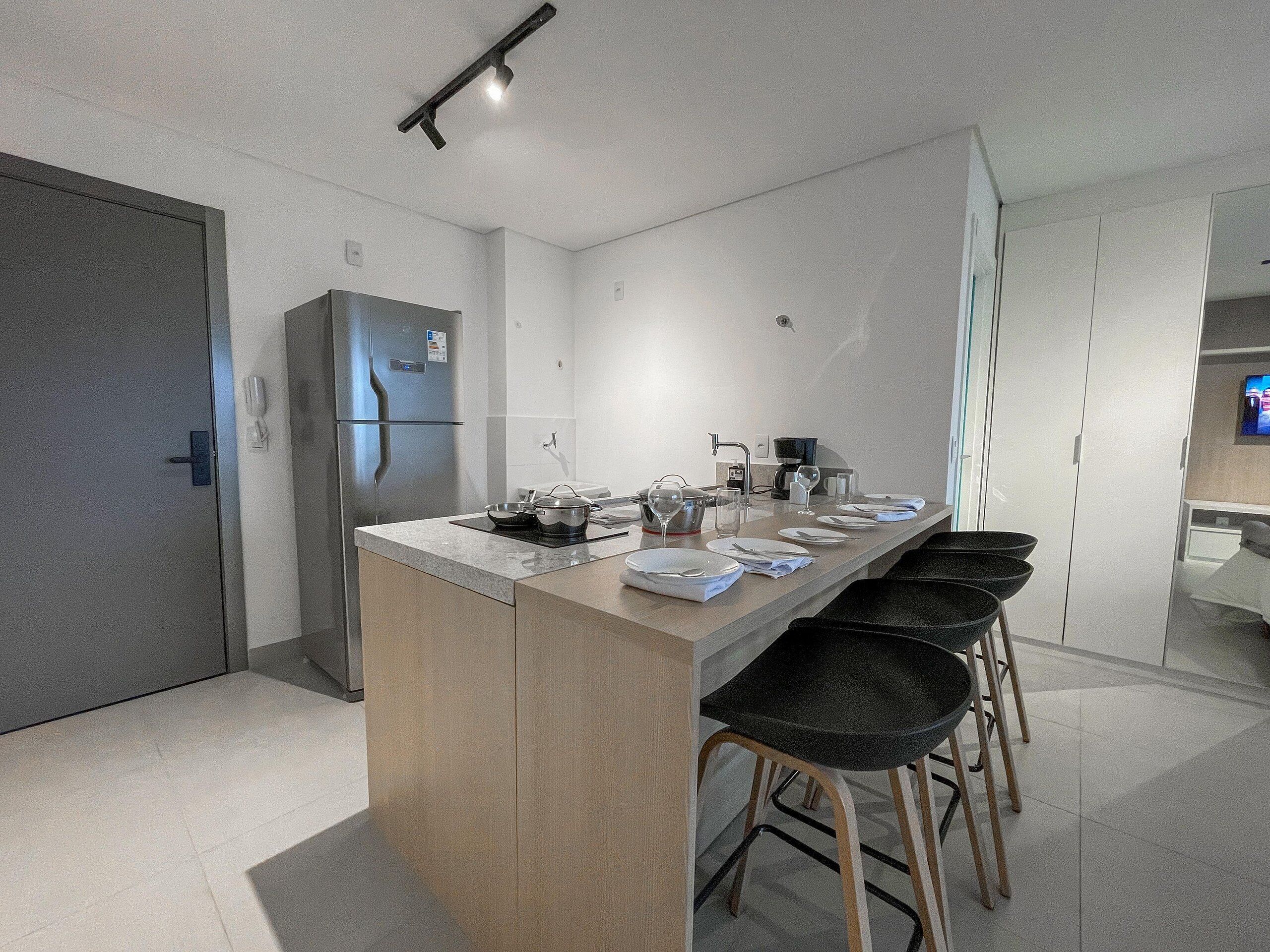 A modern kitchen with a central island, stainless steel appliances, and bar stools.