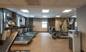Ein Fitnessstudio mit Laufbändern, Crosstrainern und einer Trinkbrunnen.