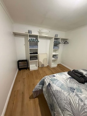 A bedroom with a bed, a wardrobe, and a shoe rack.