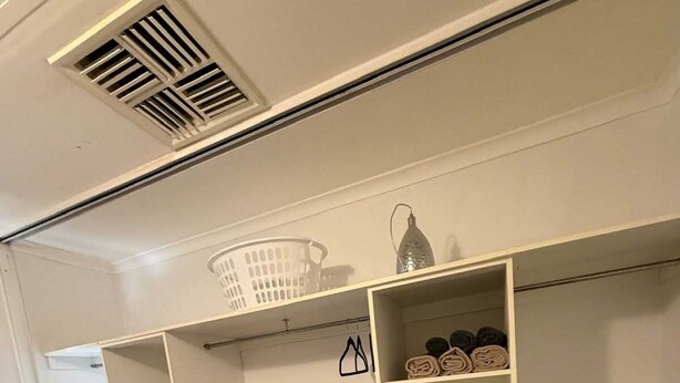 Una habitación con armario empotrado, piso de madera y un respiradero en el techo.