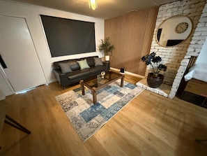 A living room with a sofa, coffee table, and a potted plant.