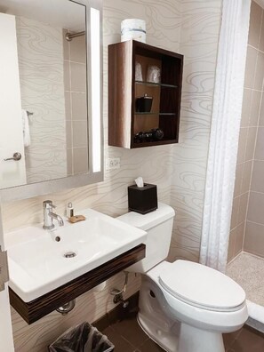 Ein modernes Badezimmer mit einem weißen Waschbecken, einem Spiegel, einer Toilette und einem Holzschrank über dem Waschbecken.