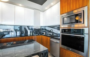 A modern kitchen with white cabinets, a black marble countertop, and stainless steel appliances including a microwave and oven. - Casa Mirador Luxury 3 bedroom Condo, Panoramic Ocean Views (Puerto Vallarta)