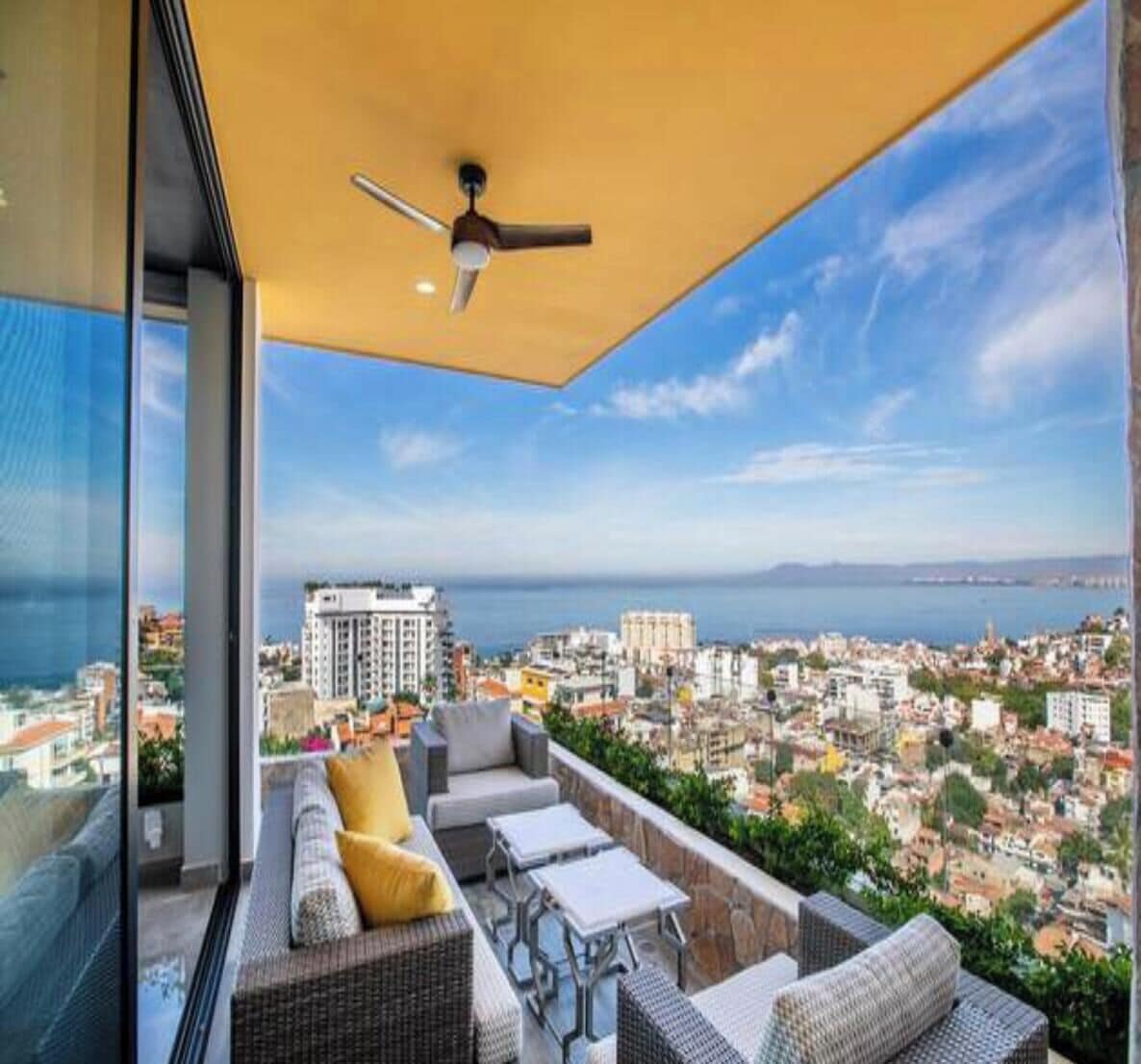 A balcony with outdoor furniture, a ceiling fan, and a cityscape view.